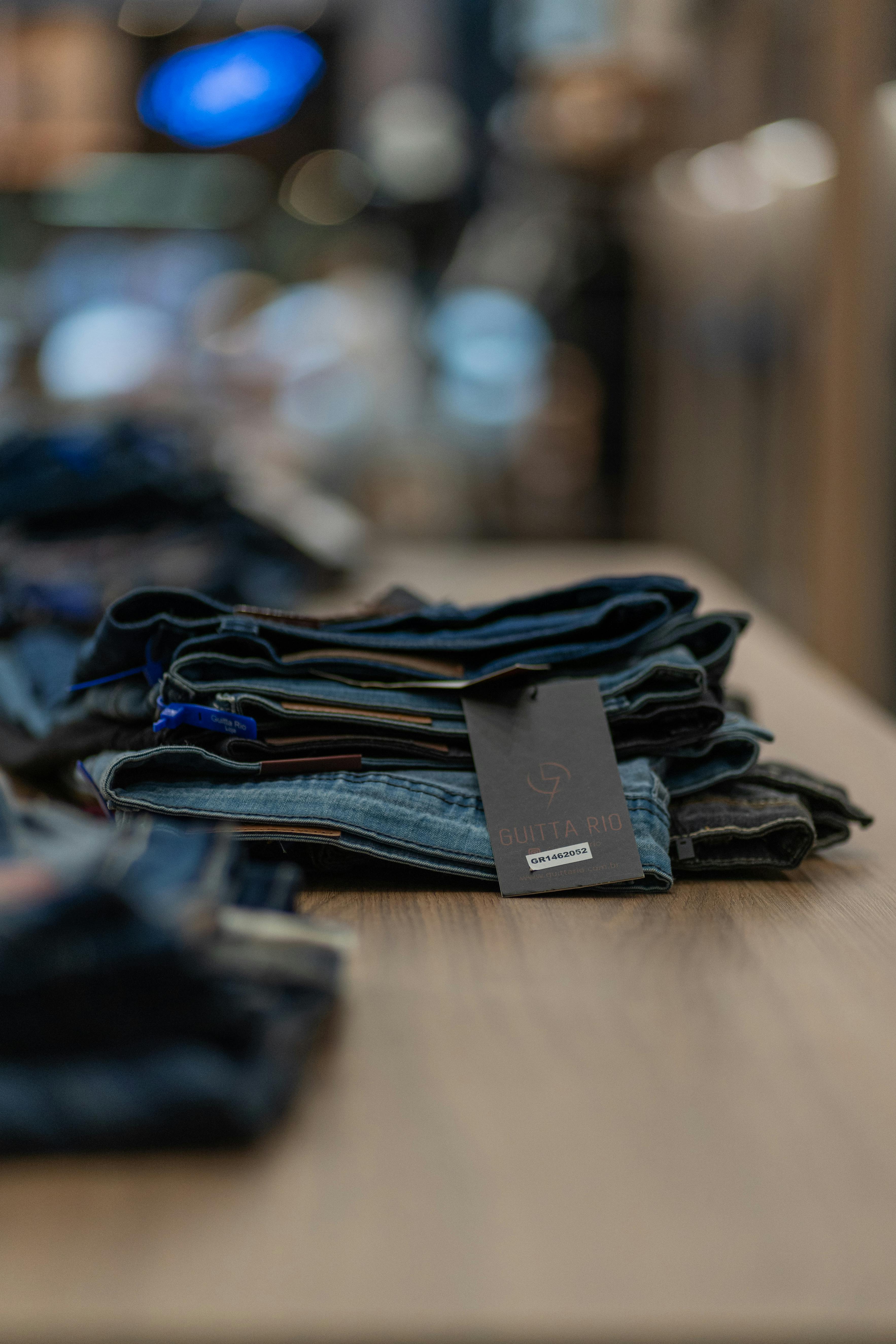 Close-up of folded jeans on a wooden table in a retail store, showcasing fashion and retail details.