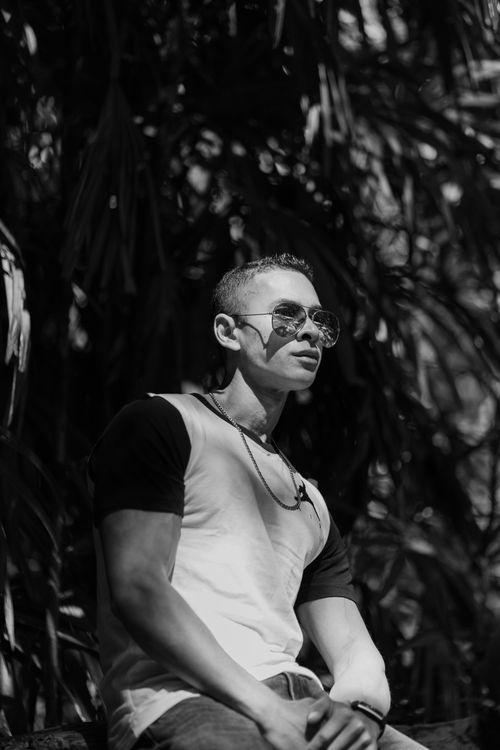 Free Black and white portrait of a man posing in sunglasses, set against an outdoor backdrop. Fashionable and modern. Stock Photo