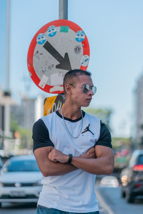 Man in Sunglasses and T-shirt Posing by Road Sign