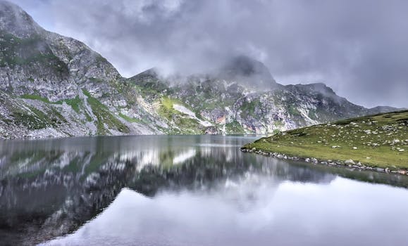 Scenic view of a tranquil lake surrounded by misty mountains in the Rila Mountains, Bulgaria. by Bob Krustev