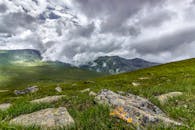 令人惊叹的山地景观，与戏剧性的云、岩石和绿草相映成趣