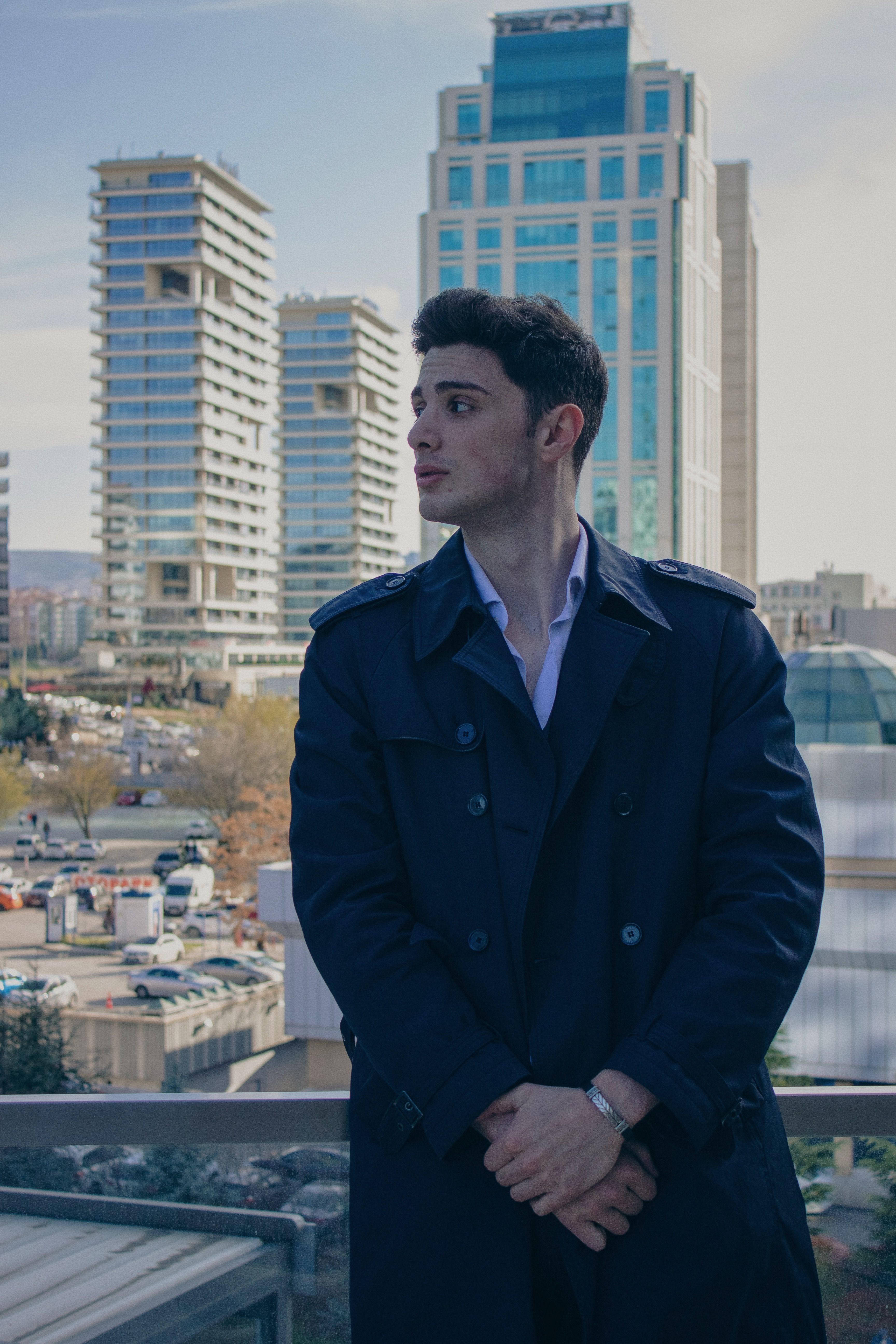 A man in a trench coat standing on a balcony · Free Stock Photo