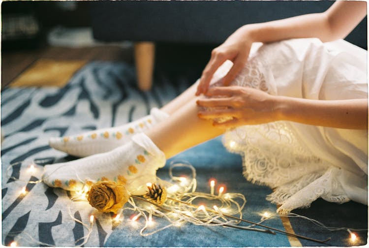 Woman In Retro Dress And Socks Sitting On Floor With Lights