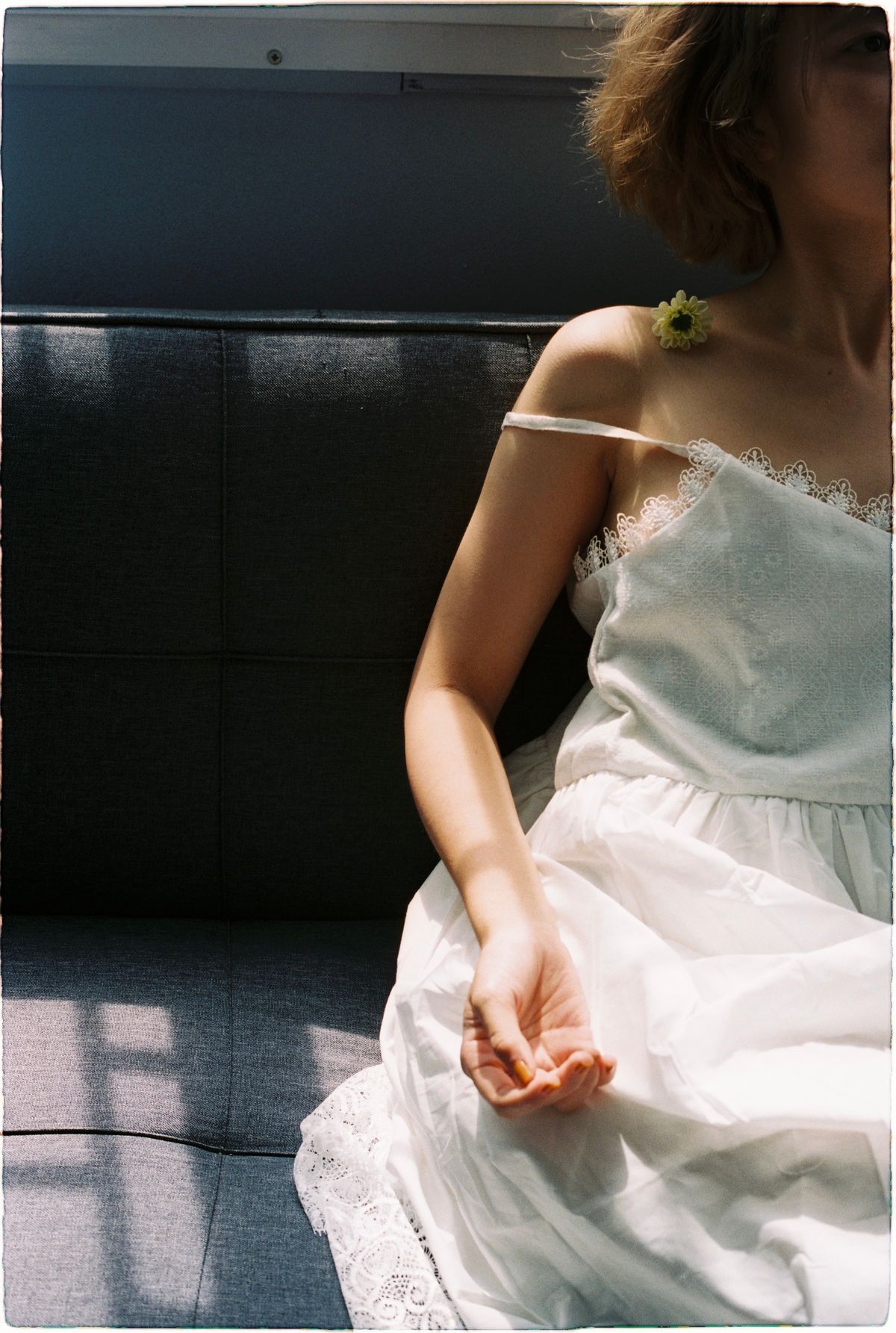 A woman with a flower sitting in soft light — the romance of the broderie hour