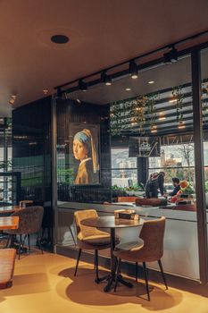 Cozy restaurant interior featuring 'Girl with a Pearl Earring' painting and modern decor elements.
