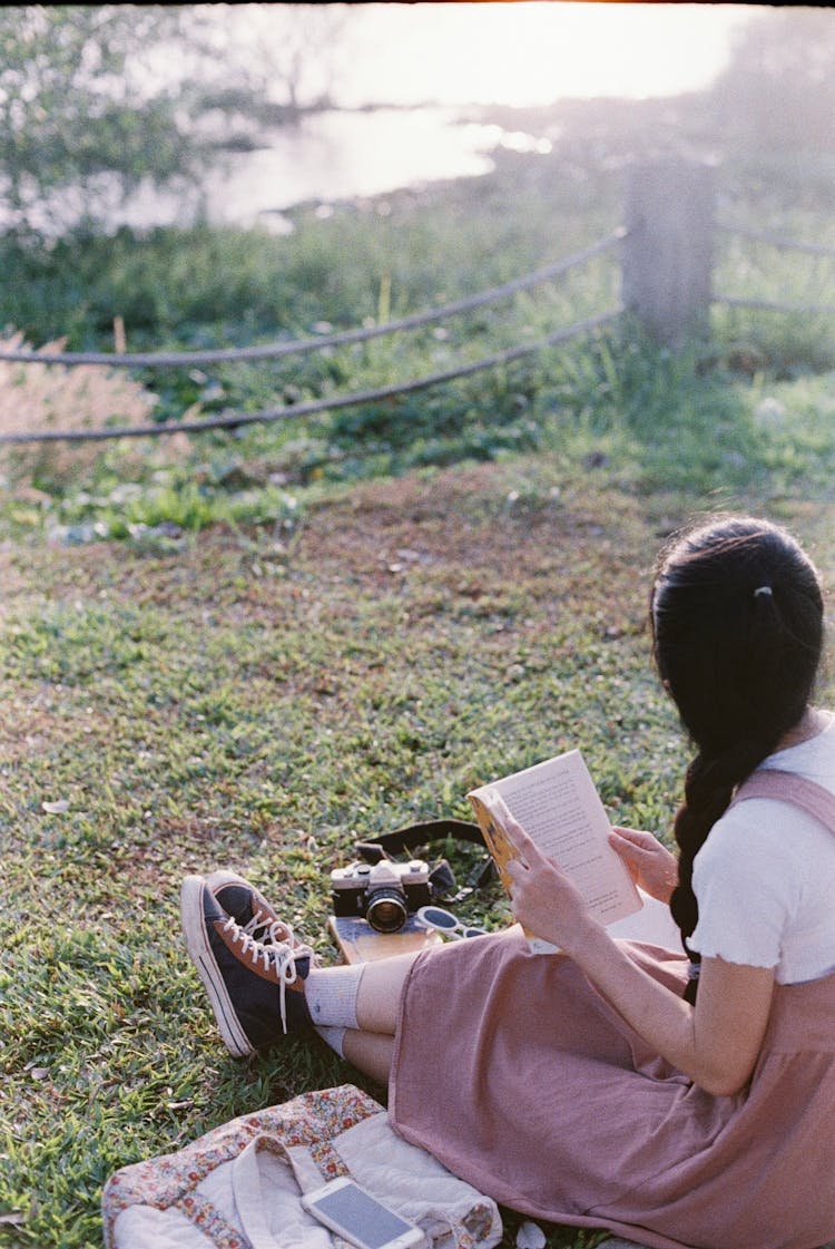 Girl Sitting On Grass Reading Book