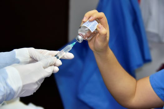 Close-up of healthcare worker filling a syringe from a vial, demonstrating vaccination or medical procedure.