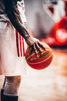 Close-up of a tattooed basketball player holding a ball indoors in São Paulo, Brazil.