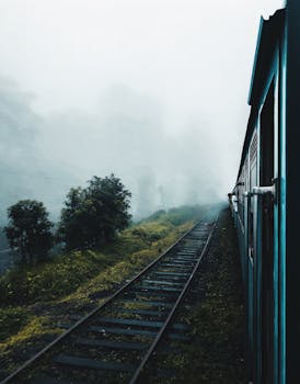 一列火车穿过雾气弥漫的乡村，铁轨消失在雾气中