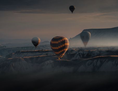 Hot air balloons soar over Cappadocia's scenic landscape at sunrise, offering a breathtaking view.
