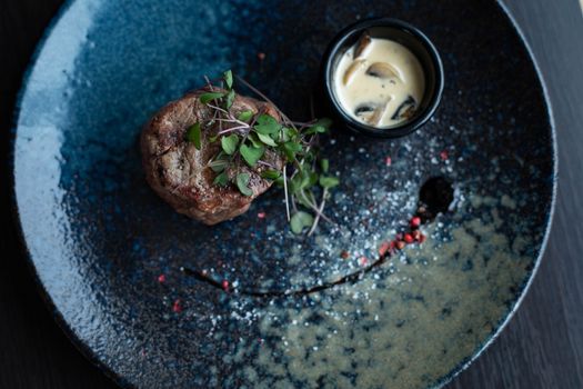 Elegant plated steak dish garnished with microgreens and served with creamy mushroom sauce.