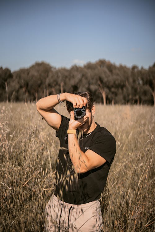 Man on a Field in Summer Taking a Picture with a Camera 