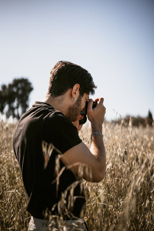Man on a Field in Summer Taking a Picture with a Camera 
