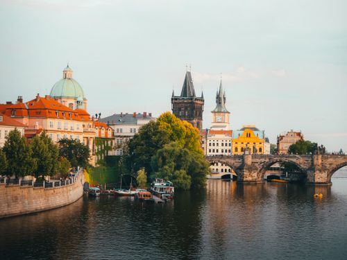 Free Scenic view of Charles Bridge and historical buildings of Prague at sunset with reflections in the river. Stock Photo