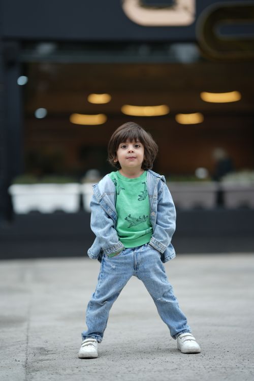Free Young boy in denim jacket and jeans posing confidently in an urban setting. Stock Photo