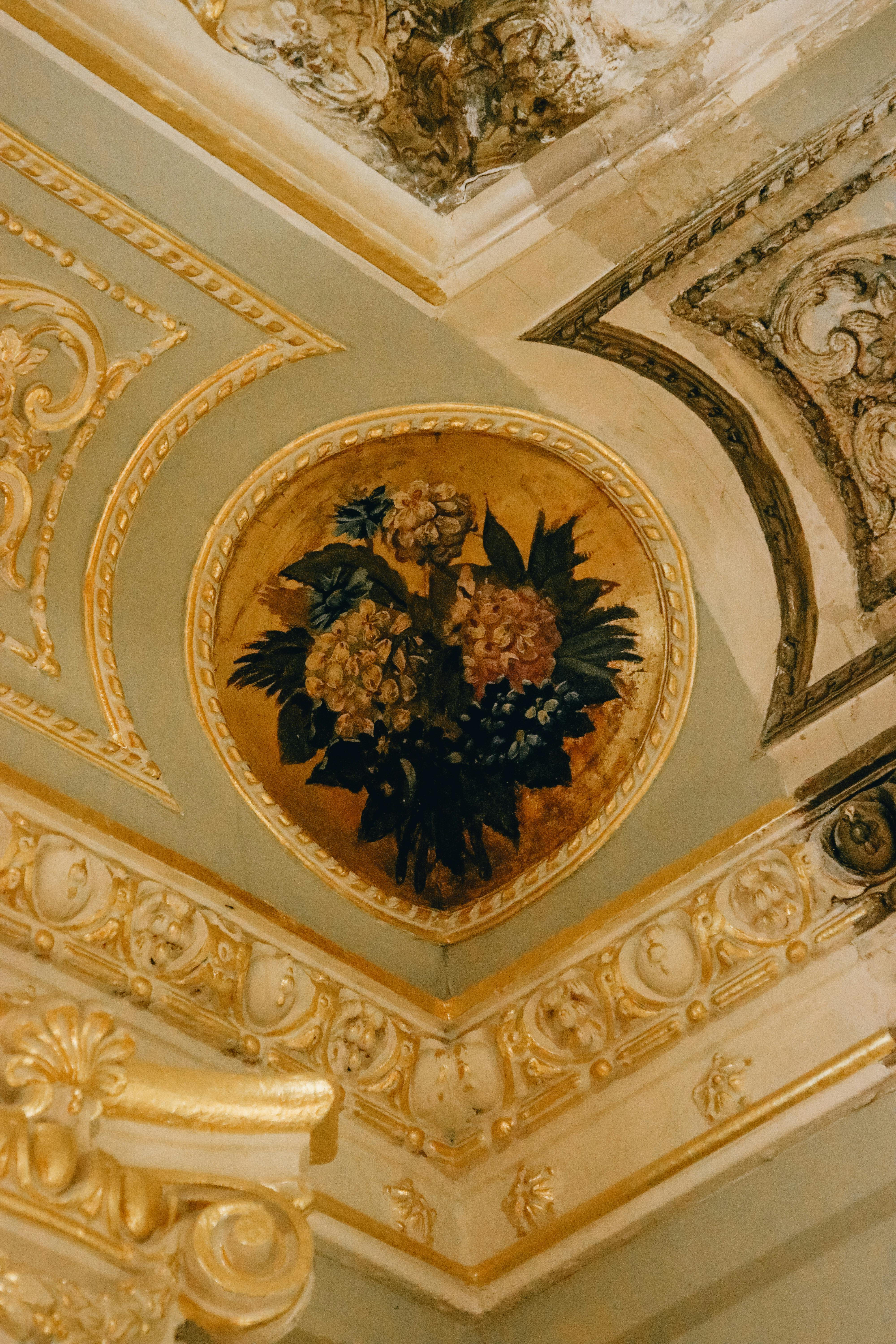 Close-up of an ornate ceiling with luxurious floral artwork in a palace interior.