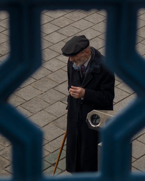 An Elderly Man in a Black Coat Smoking a Cigarette 