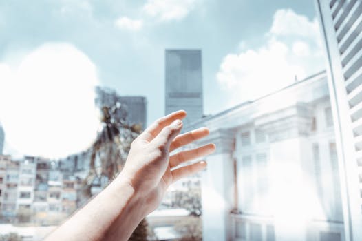 一只手伸向城市景观中的玻璃建筑和蓝天
