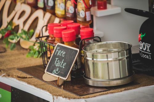 Free Close-up of spice bottles with free tasting sign on a rustic market counter. Stock Photo