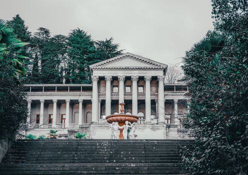 Fountain with Sculptures near Old Building in Garden 