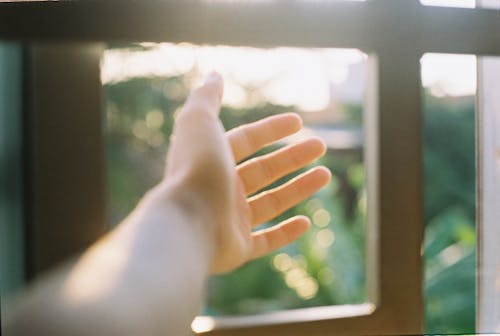 Free Person Stretching Hand in Window to Sun Stock Photo