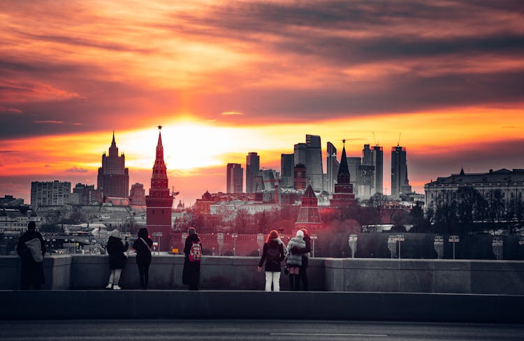 People Watching Sunset Above City In Evening 