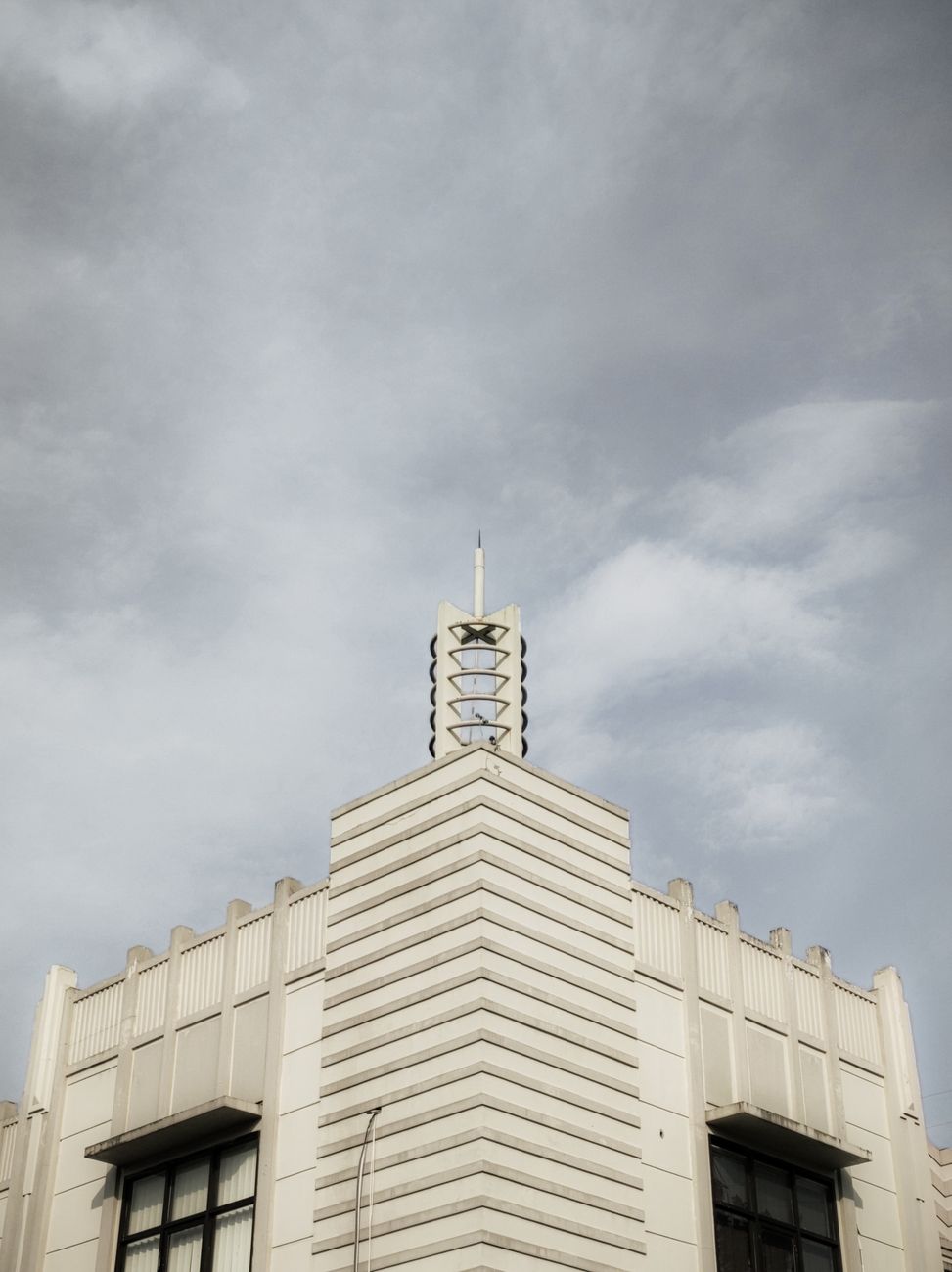 A striking art deco building with unique architecture under a cloudy sky, viewed from a low angle.. pexels, striking, deco