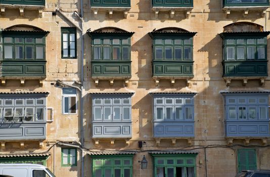 Charming traditional balconies on a Maltese facade in the sunlit streets of La Valletta.
