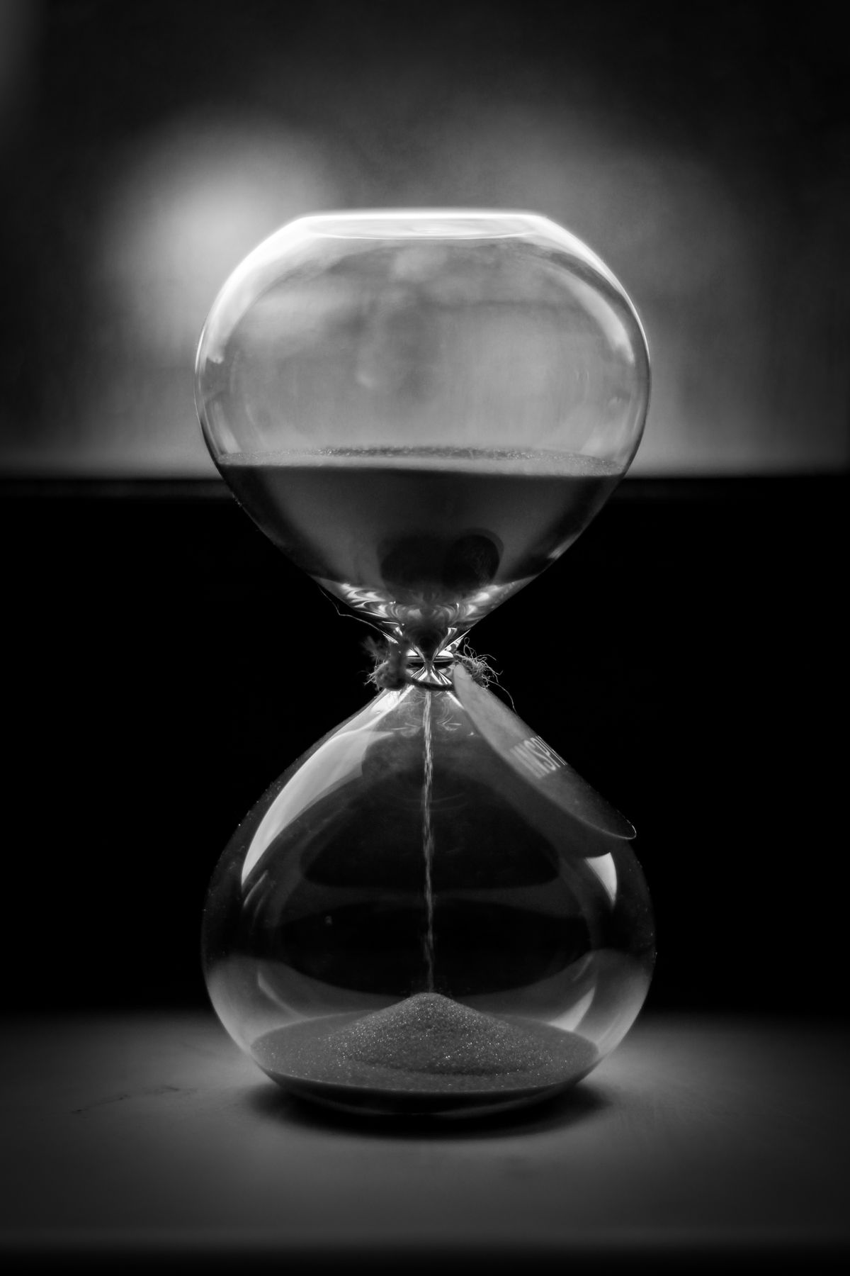 A black and white hourglass with sand running through it