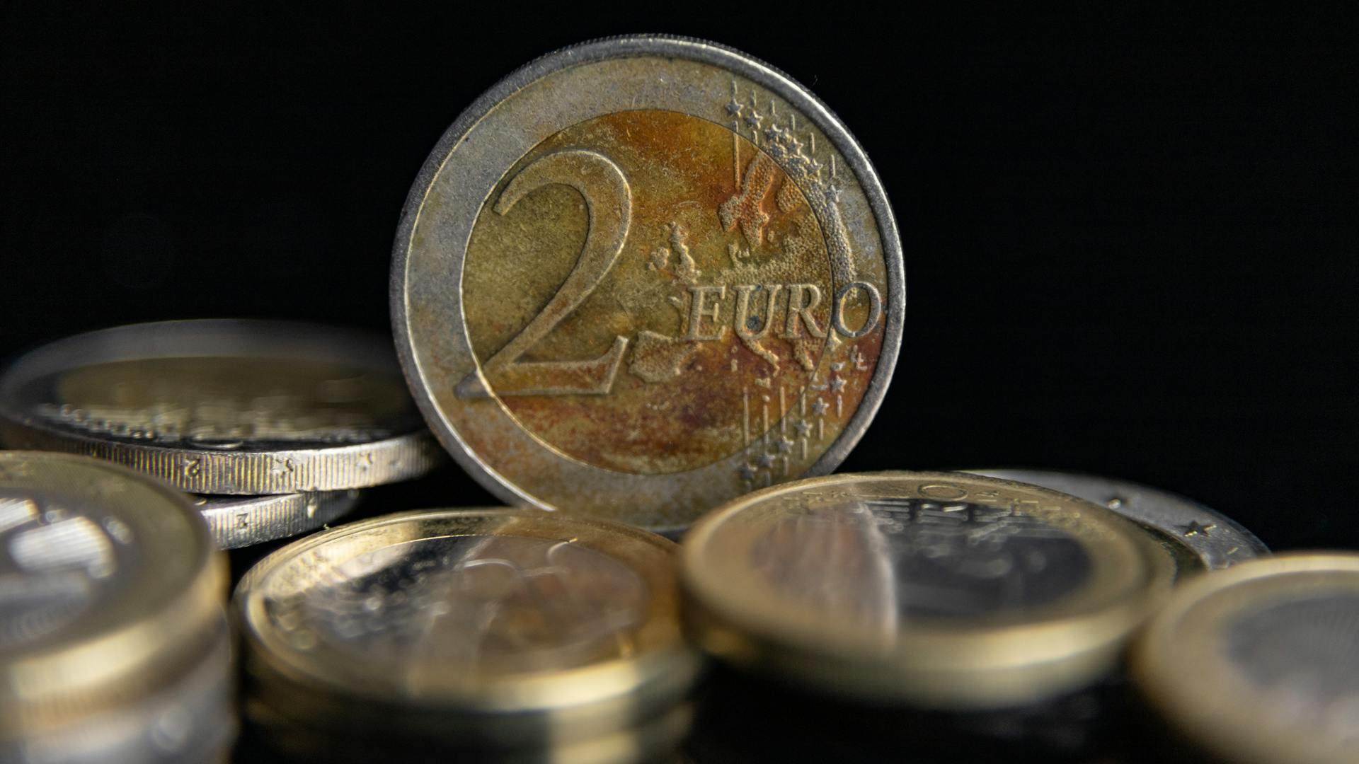 Detailed macro shot of euro coins stacked against a black backdrop.