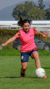 Woman practicing soccer outdoors with a focus on control and agility on a sunny day.