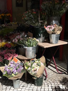 A charming street market stall displaying colorful flower bouquets in metal buckets, perfect for urban decor.