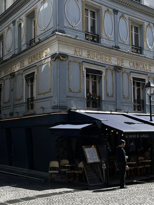 Free Discover the iconic Au Rocher de Cancale on a sunlit Parisian street corner, perfect for a city escape. Stock Photo