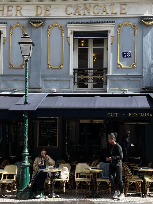Free Classic Parisian café atmosphere with patrons enjoying a relaxed day outdoors. Stock Photo