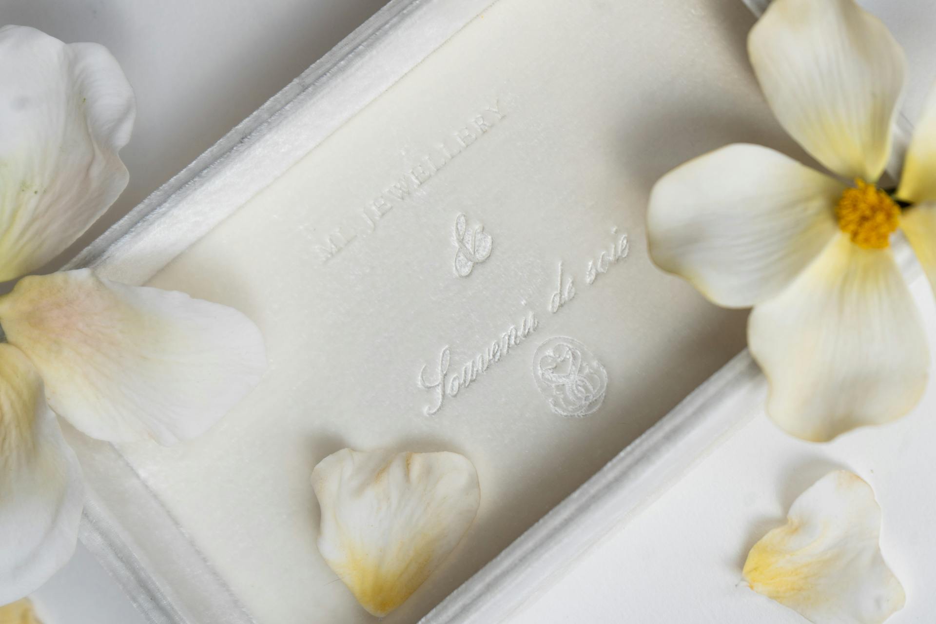 Close-up of a luxurious jewelry package adorned with white petals.