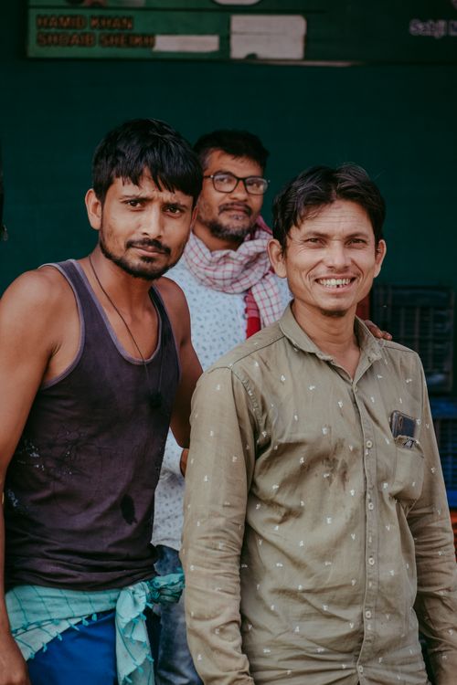 Free Three men smiling in a relaxed pose, captured in a vibrant outdoor setting. Stock Photo