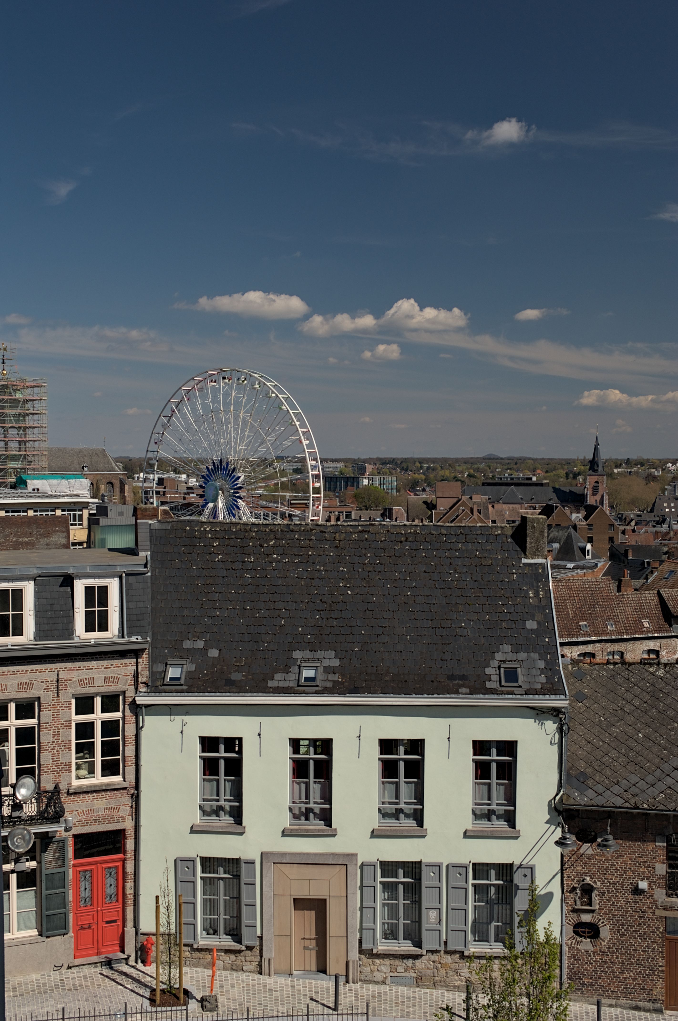 A charming old town view featuring historic buildings and a distant Ferris wheel under a clear summer sky.