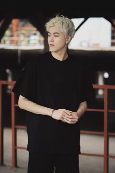 Portrait of a fashion model with dyed hair in a black t-shirt posing outdoors.