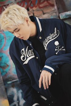 Stylish blonde model posing in a graffiti-covered urban setting.