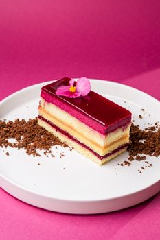 A vibrant and delicious layered cake topped with a pink edible flower, perfect for indulgence.