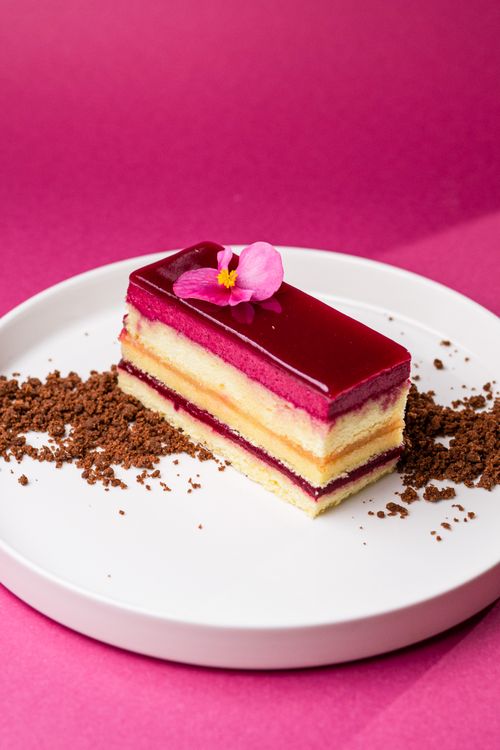 Free A vibrant and delicious layered cake topped with a pink edible flower, perfect for indulgence. Stock Photo
