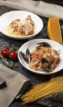 Top-down view of various pasta dishes with fresh ingredients like tomatoes and cheese.