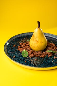 A single pear artfully placed on a blue plate with a bold yellow background.