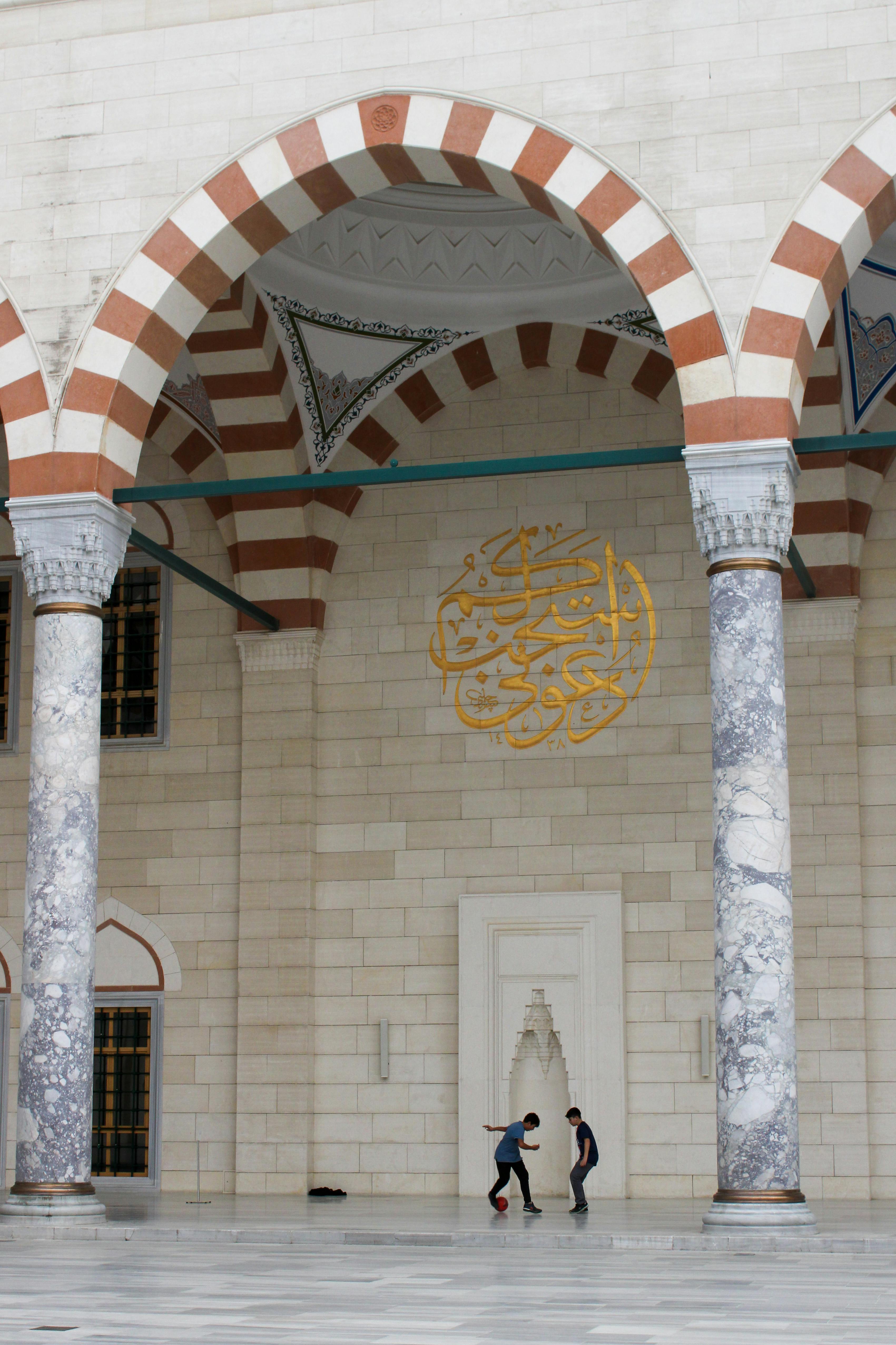 two people walking in front of a mosque