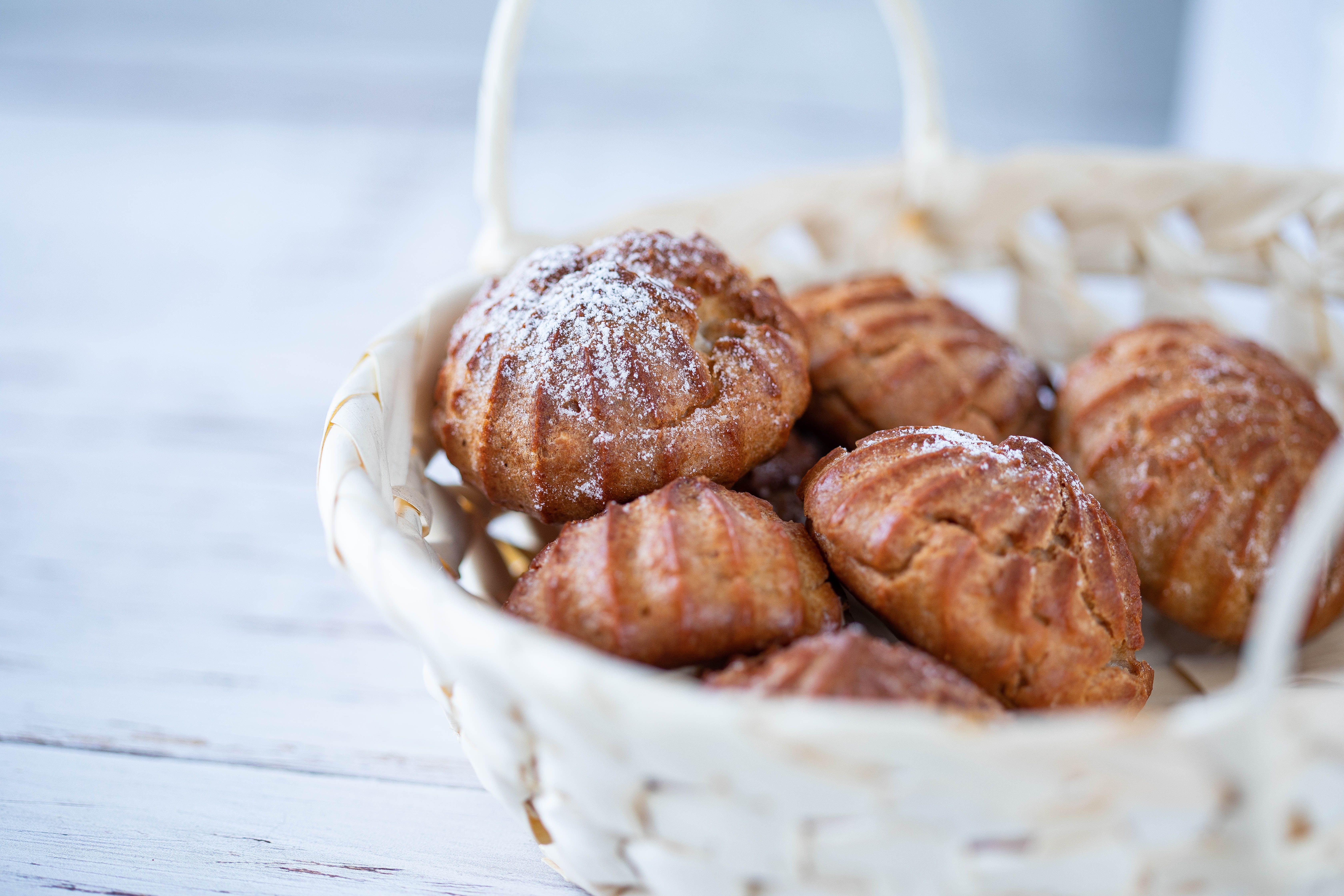 Delicious pastries in a wicker basket with a touch of powdered sugar, perfect for breakfast.