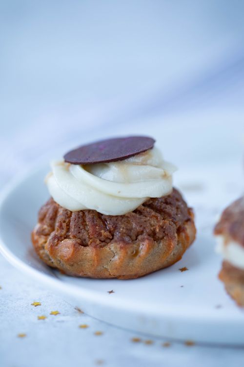 Free Close-up of a cream-filled choux pastry topped with chocolate on a white plate. Stock Photo