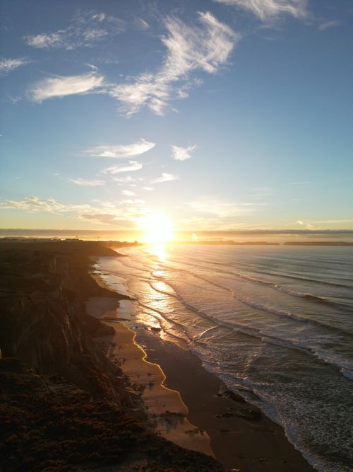 Free Aerial view of a serene sunrise over Peniche beach, Portugal, with golden sands and gentle waves. Stock Photo