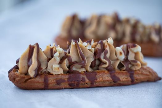 Close-up of a delicious eclair drizzled with chocolate and topped with cream, perfect dessert treat.