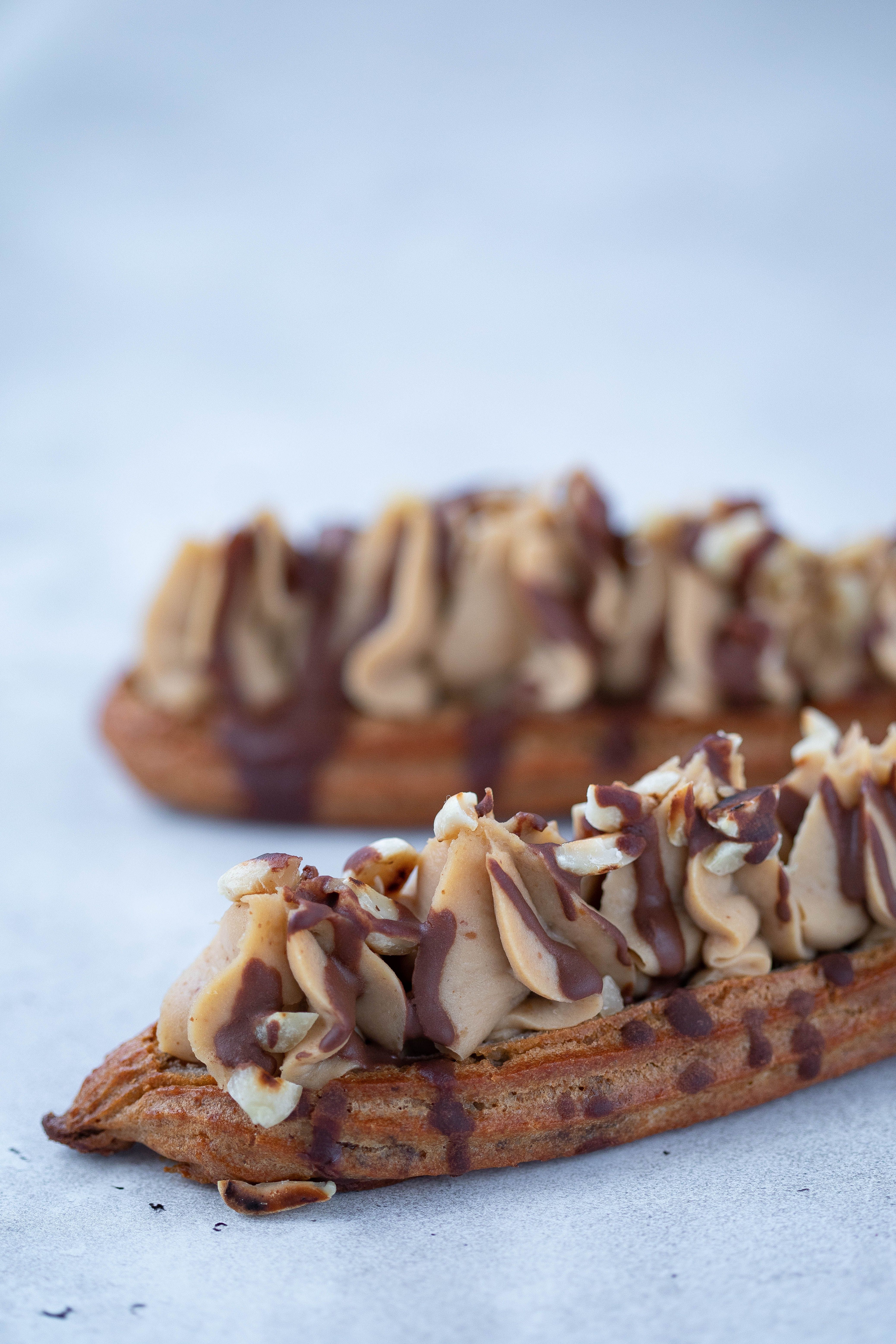 Close-up of delicious chocolate drizzled eclairs on a light background.