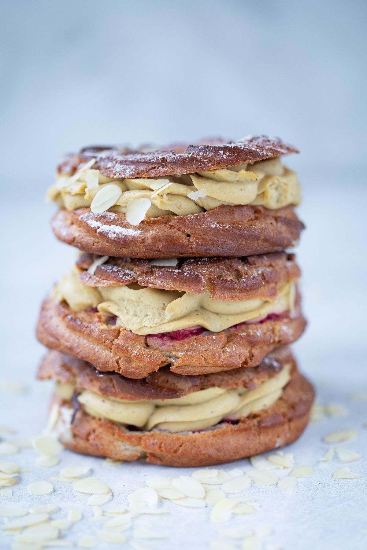 Three Paris-Brest stacked, cracked caramel tops facing out.